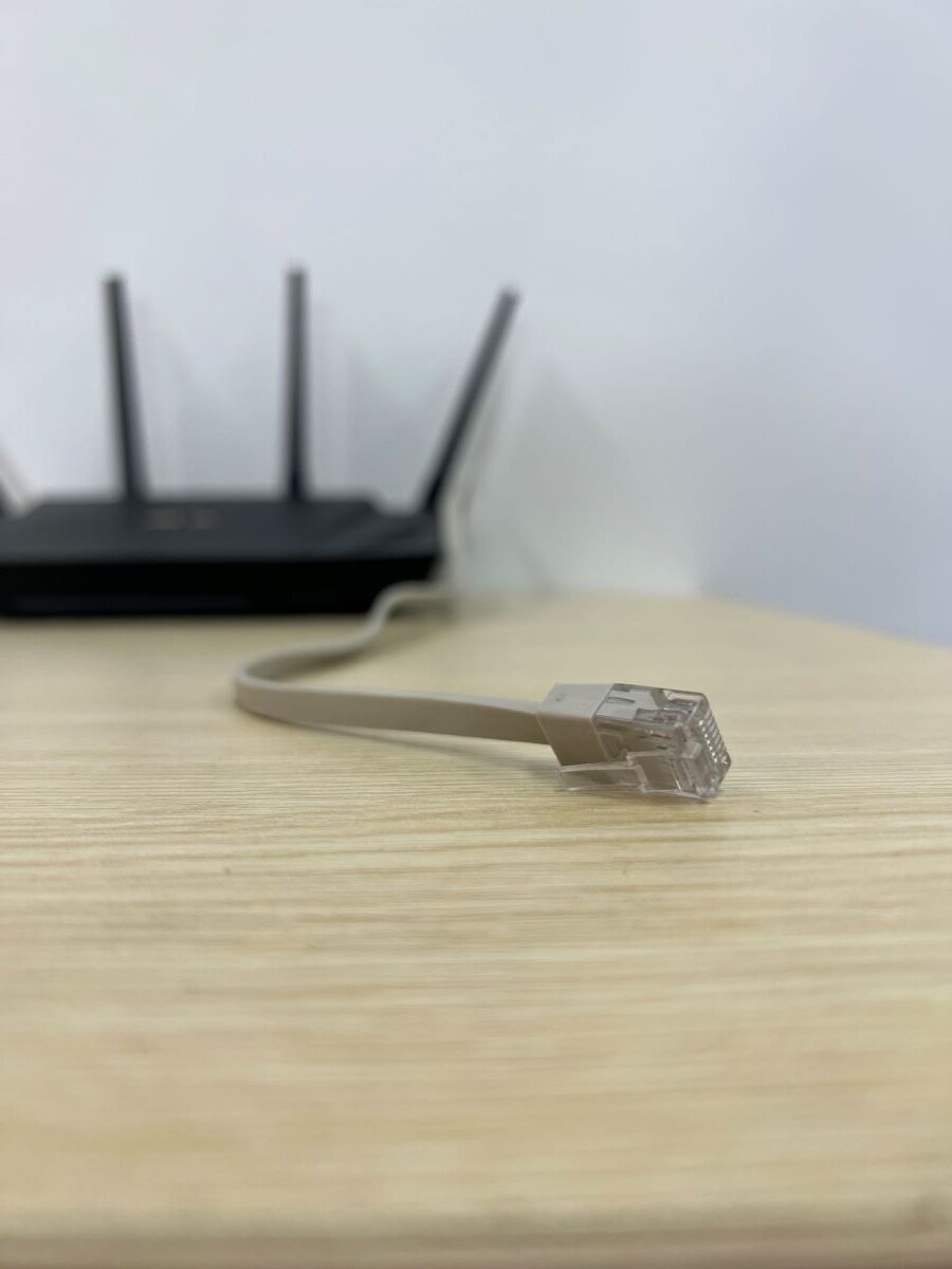 Ethernet cable with Asus router at the background on a wooden table