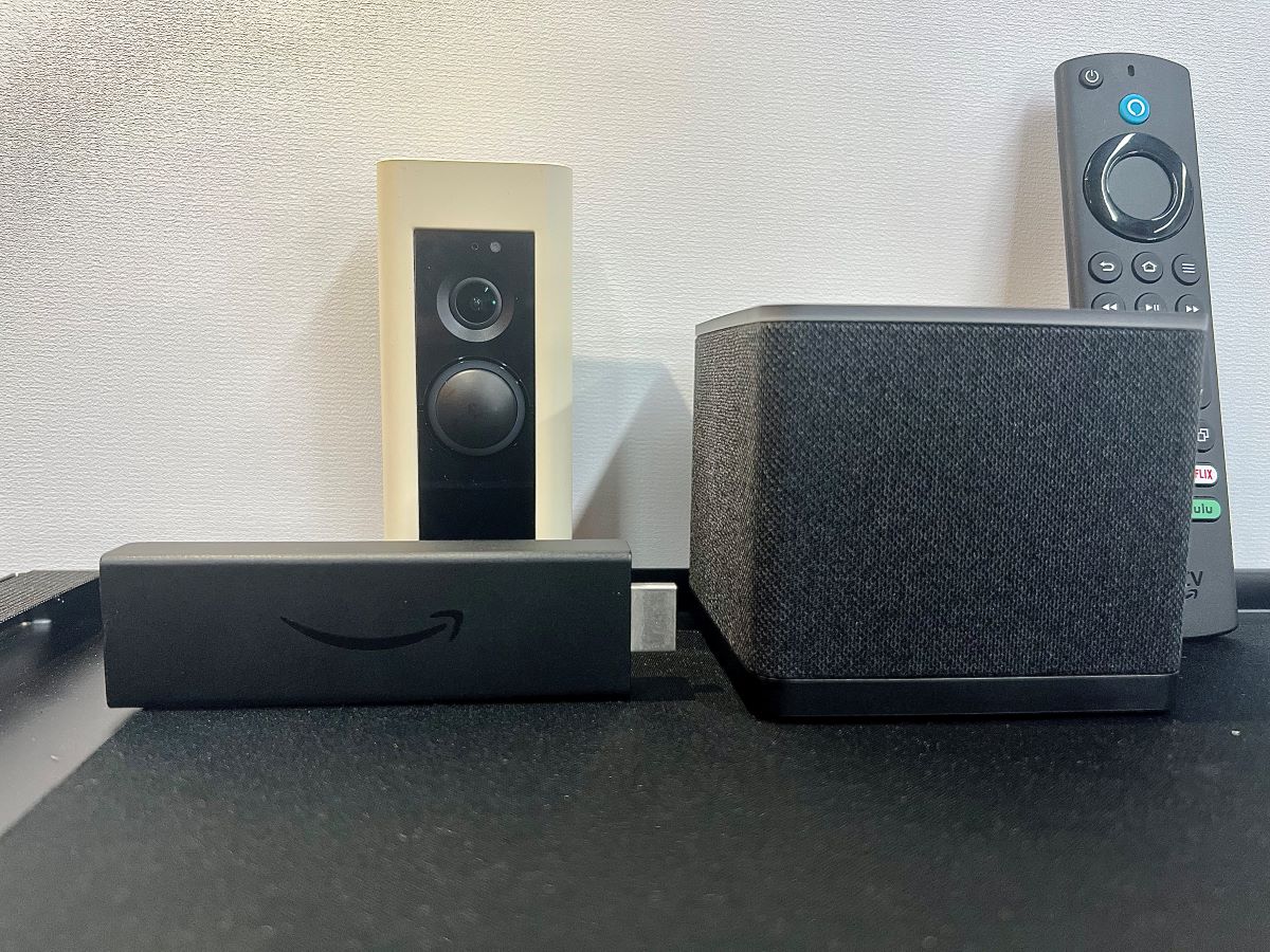 ring doorbell, fire tv stick, cube and its remote are on a tripod stand
