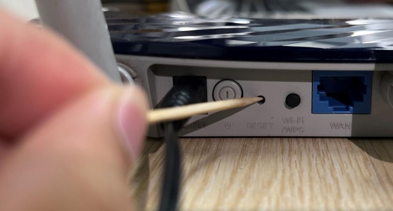 use a toothpick to press the Reset button on the TP-Link router