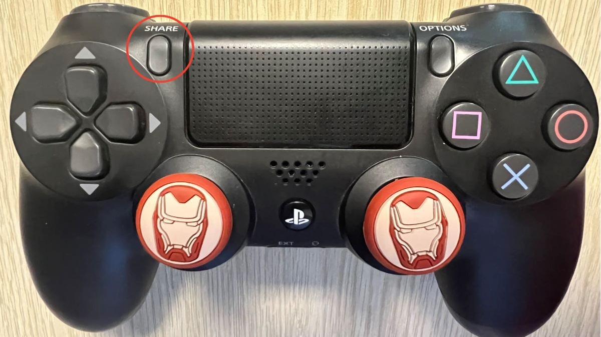 The PS4 controller with the share button is highlighted with a red circle on a wooden table
