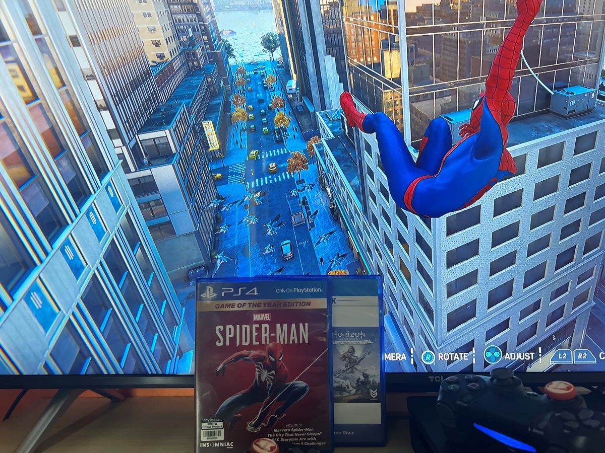 The Spider-Man game on PS4 with the cover box and the horizontal near to the PS4 controller