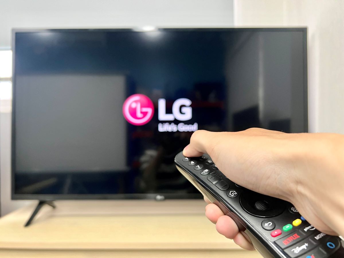a hand turning off an lg tv