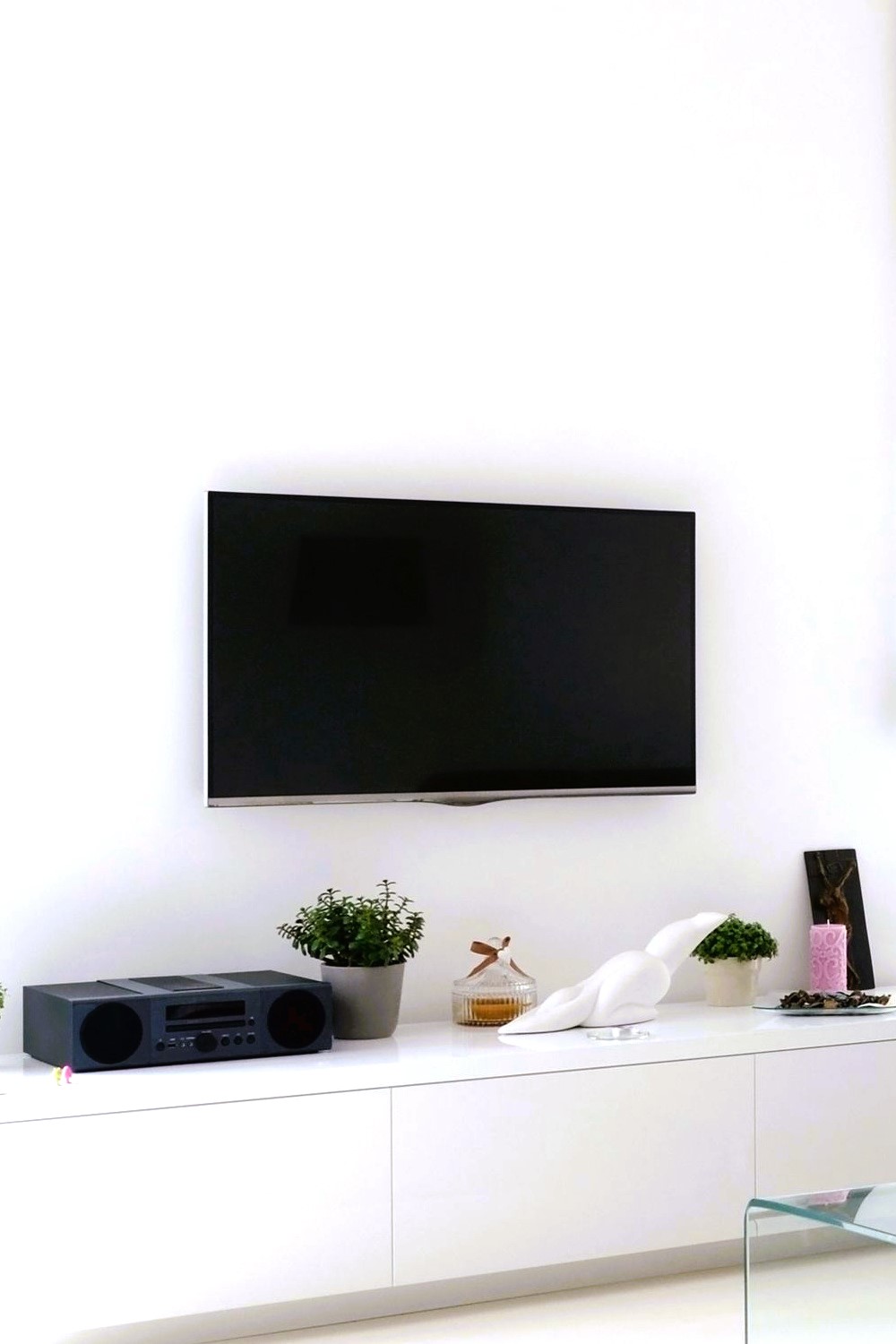 small tree pots beneath a mounted tv 