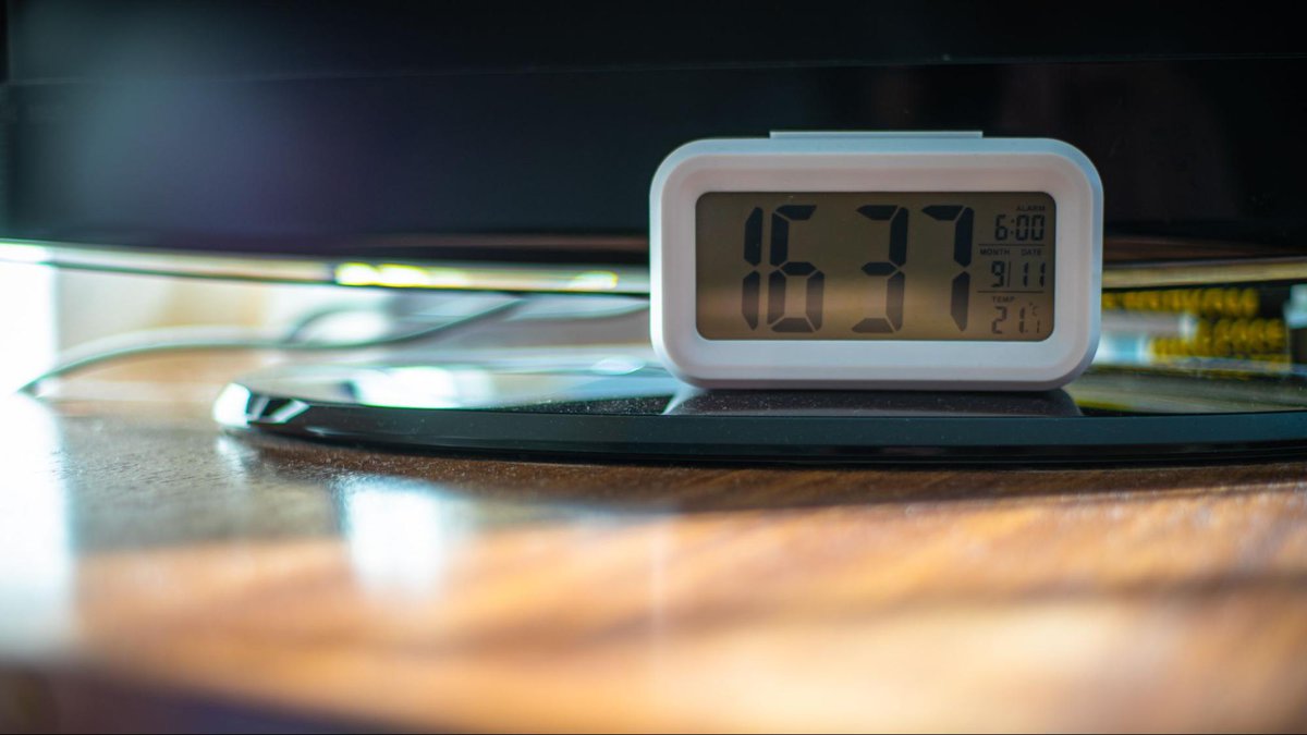 an digital clock under a tv 