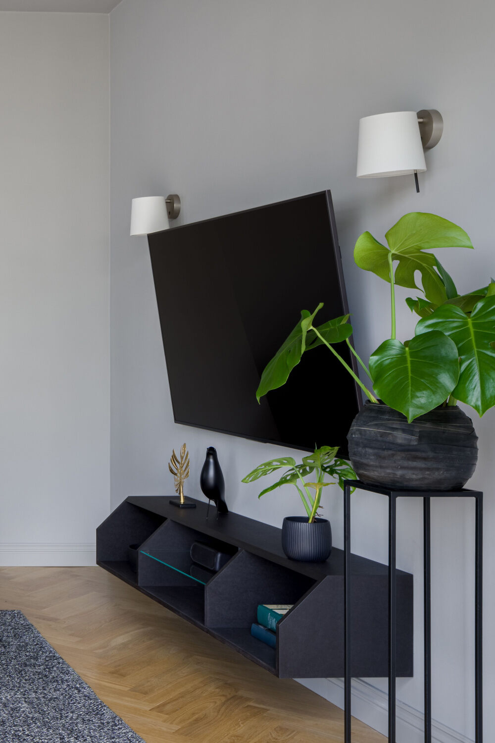 a mounted tv above a black shelf