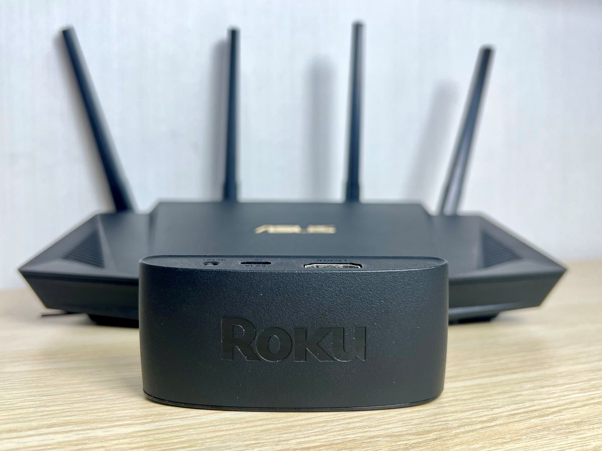 a roku is standing in front of an asus router on a table