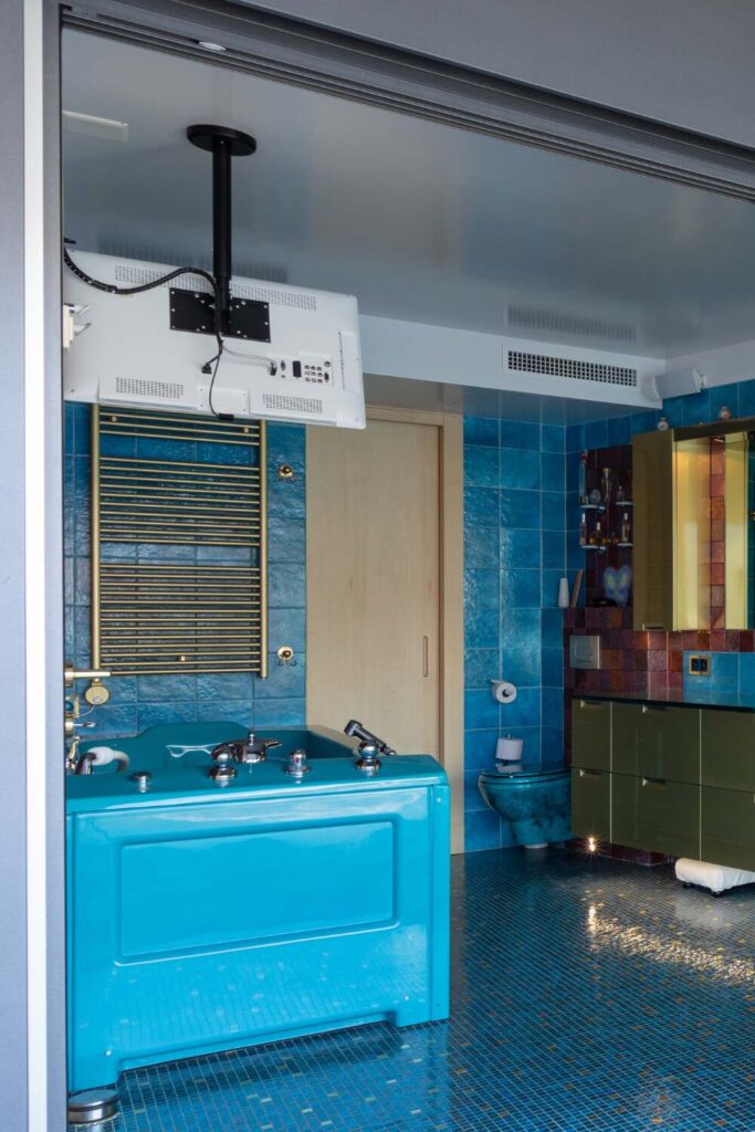 blue bathroom with a TV mounted to the ceiling