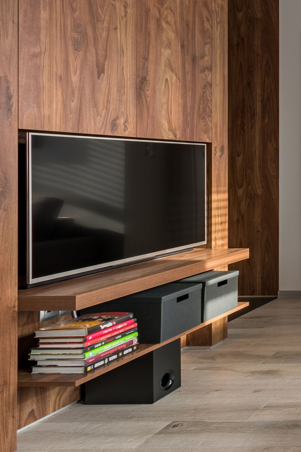 TV mounted above 2 shelves and some books