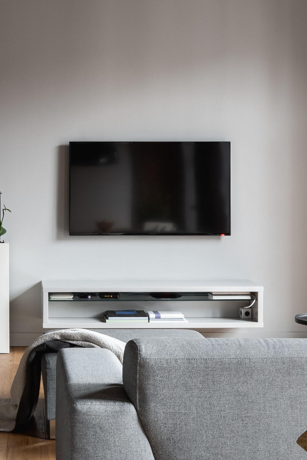 mounted tv on the wall, above a shelf