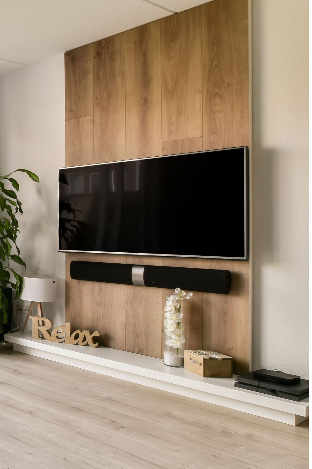 tv mounted on the wall above a soundbar and a shelf
