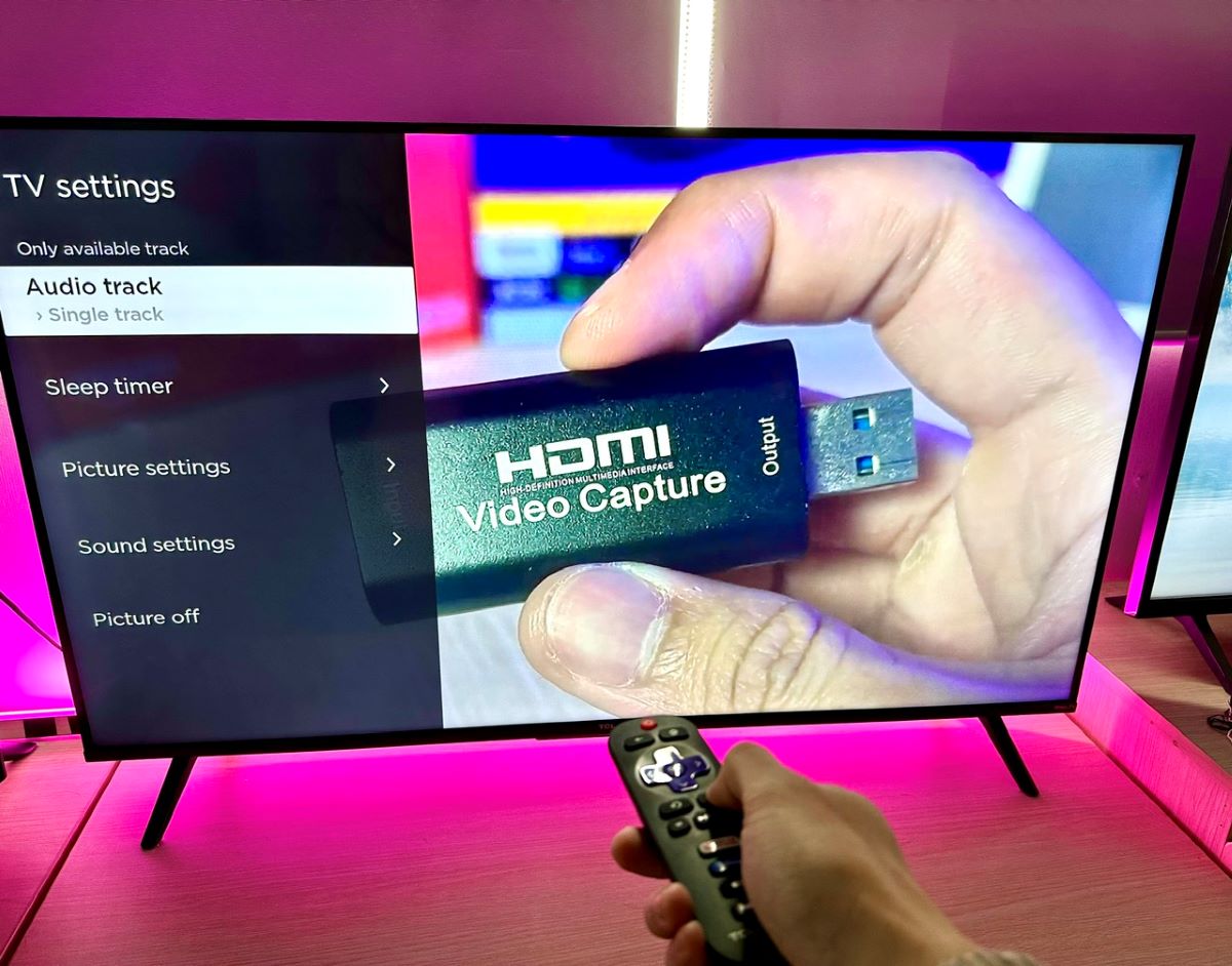 a hand pressing the asterisk button on a tcl roku tv remote