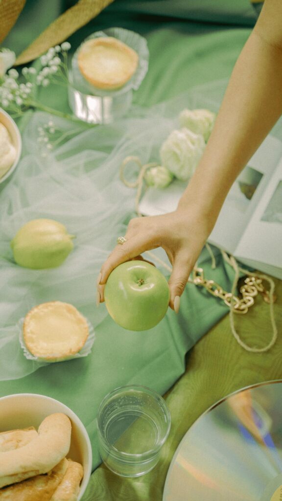 A Female Hand Holding a Green Apple on Green Fabric
